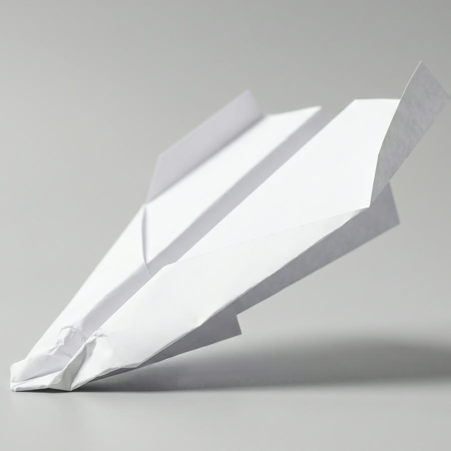 A paper dart that has crash-landed nose-first, nose crumpled and tail in the air